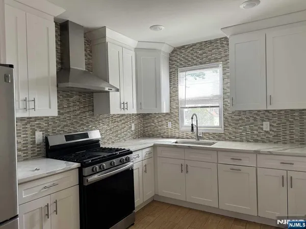 a kitchen with white cabinets appliances a sink and a window