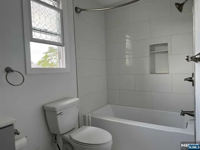 a white toilet and tub sitting next to a window