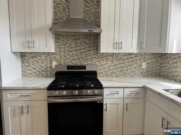 a kitchen with granite countertop white cabinets and black appliances