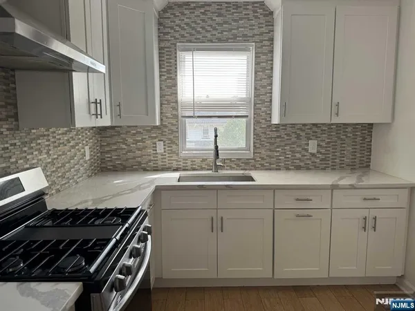 a kitchen with granite countertop a sink stove and cabinets