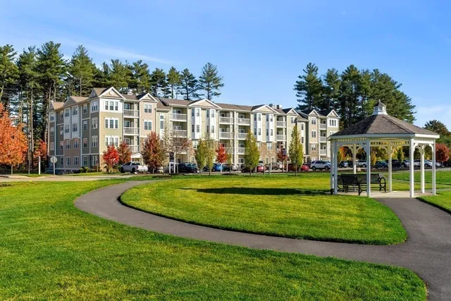 a front view of a building with a garden and trees