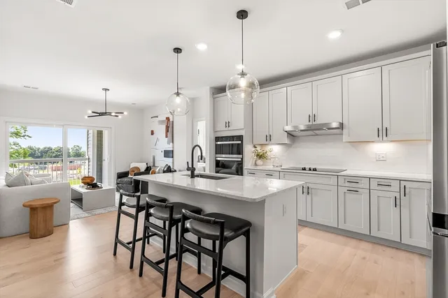 a kitchen with stainless steel appliances granite countertop a table chairs stove and white cabinets
