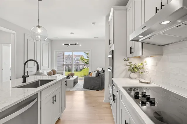 a kitchen with sink a stove and white cabinets with wooden floor