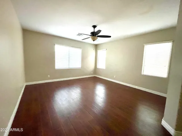 a view of empty room with wooden floor and fan