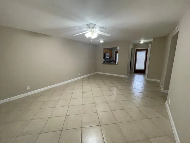 an empty room with kitchen and chandelier fan