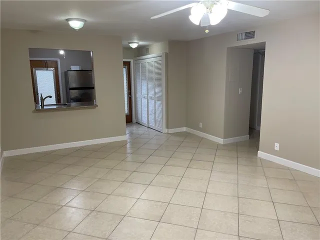 an empty room with kitchen and chandelier fan