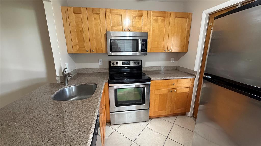 550 Southeast 2nd Avenue, Unit G5 Deerfield Beach, FL 33441 - Photo 6 of 28 a kitchen with granite countertop a stove and a microwave