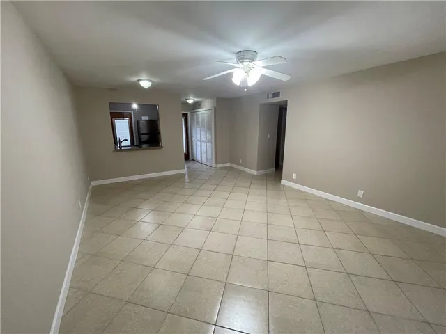 a view of an empty room with glass door and chandelier fan