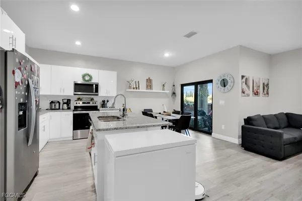 a kitchen with stainless steel appliances granite countertop a stove top oven a sink a dining table and chairs with wooden floor