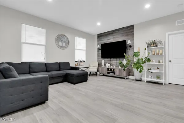 a living room with furniture a large window and wooden floor