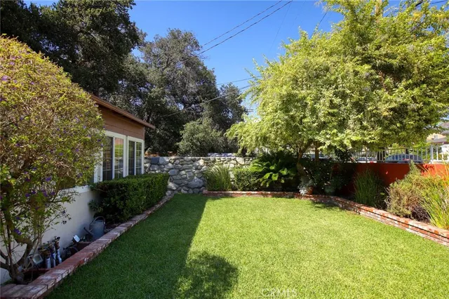 a view of a backyard with potted plants and large trees