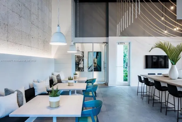 a room with lots of tables a large window and chairs