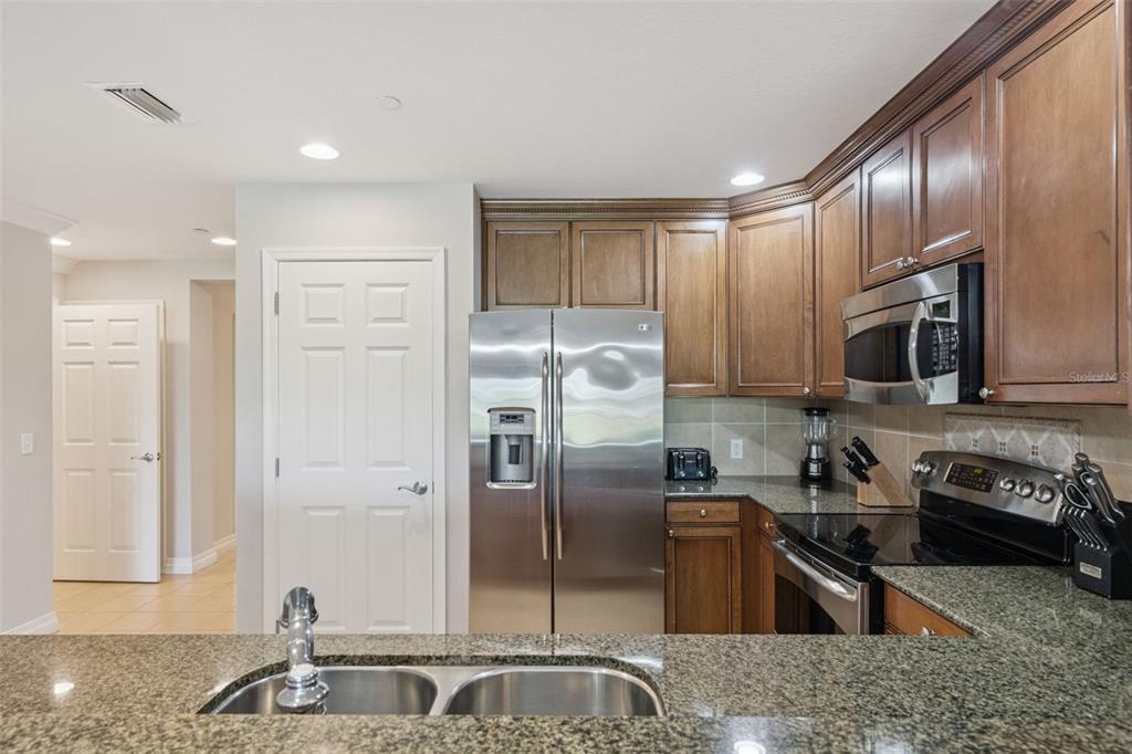 1100 Sunset View Circle, Unit 102 Reunion, FL 34747 - Photo 29 of 67 a kitchen with stainless steel appliances granite countertop a refrigerator a stove and a sink with wooden cabinets