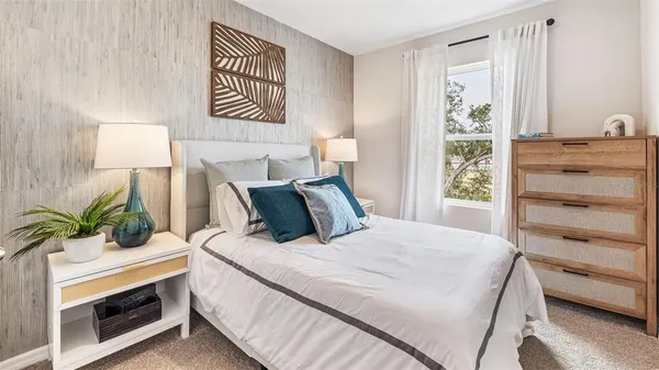 a bedroom with a bed and a potted plant on the dresser