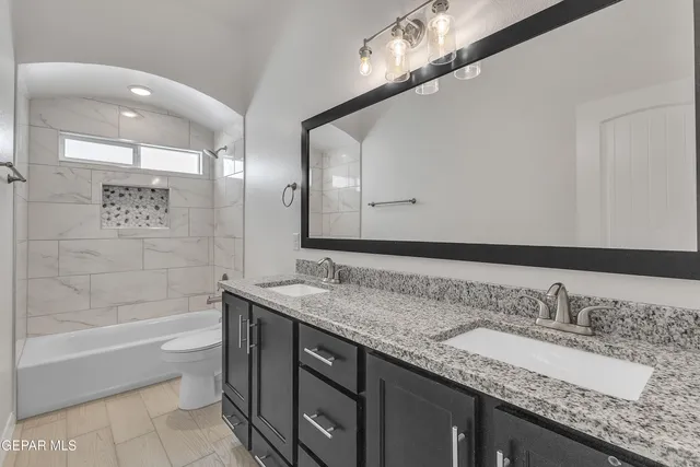 a bathroom with a granite countertop double vanity sink and mirror with bathtub