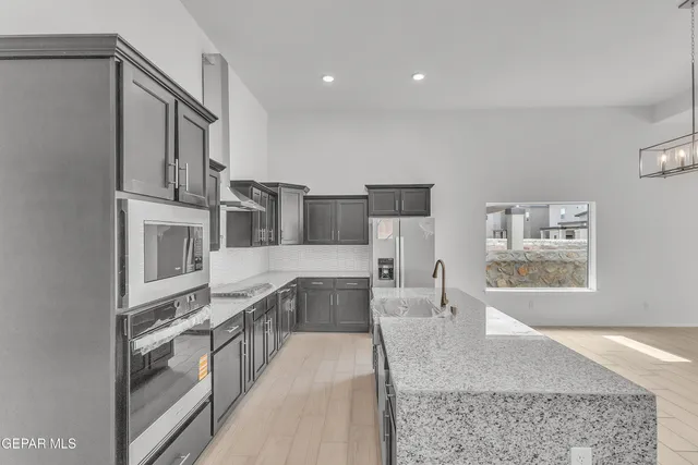 a large kitchen with stainless steel appliances granite countertop a large counter top and a stove top oven