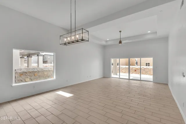 an empty room with wooden floor chandelier and windows