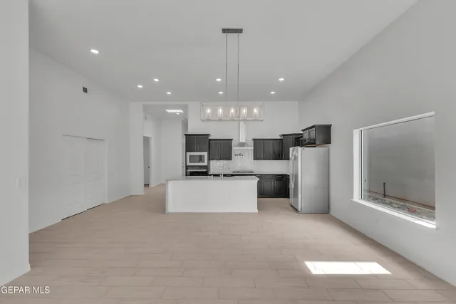 a view of a kitchen with stainless steel appliances granite countertop a large counter top a refrigerator and a fireplace