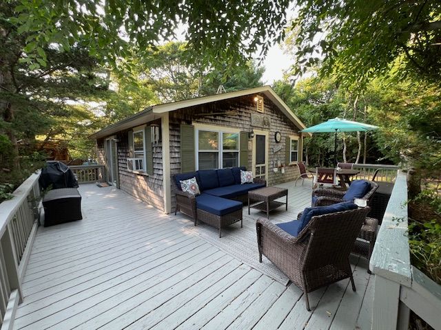 60 R Carol Lane Oak Bluffs, MA 02557 - Photo 1 of 14 a view of a roof deck with table and chairs under an umbrella with wooden floor