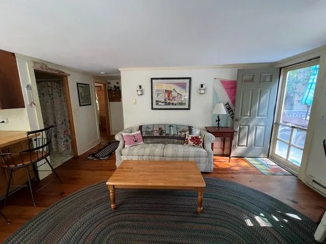 a living room with furniture a large window and wooden floor