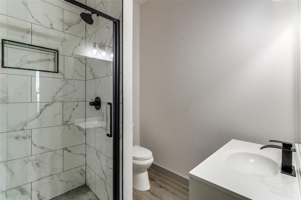 917 South Carroll Avenue Dallas, TX 75223 - Photo 19 of 30 Bathroom with vanity, a marble finish shower, light wood finished floors, and a textured wall
