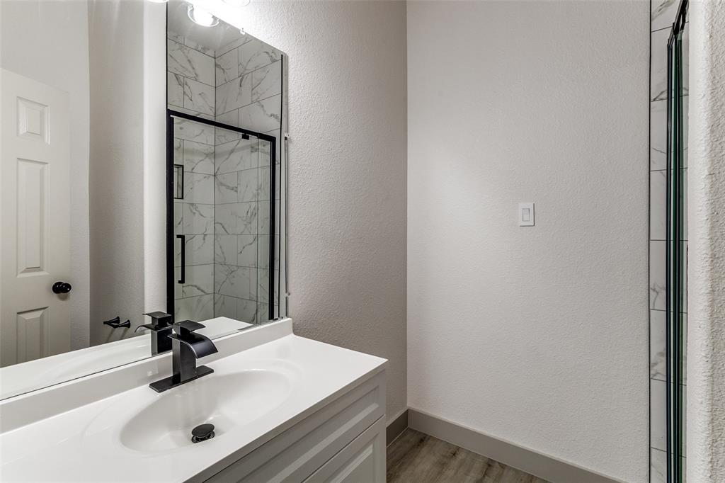 917 South Carroll Avenue Dallas, TX 75223 - Photo 27 of 30 Full bathroom featuring a textured wall, a marble finish shower, vanity, and light wood-style flooring
