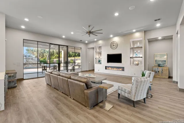 a living room with furniture large window and wooden floor