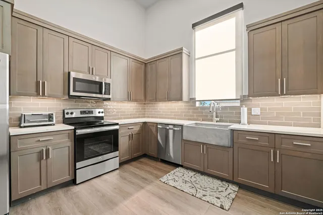 a kitchen with granite countertop a sink cabinets stainless steel appliances and a window