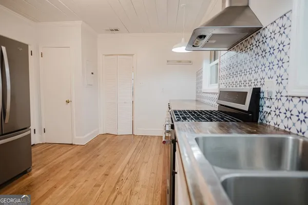 a kitchen with stainless steel appliances a sink dishwasher a refrigerator and a stove with wooden floors