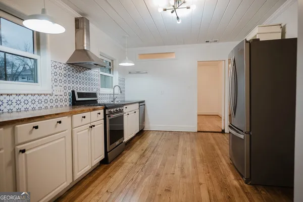 a kitchen with stainless steel appliances granite countertop a stove a sink and white cabinets