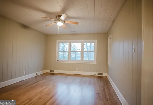 a view of an empty room with wooden floor and a window