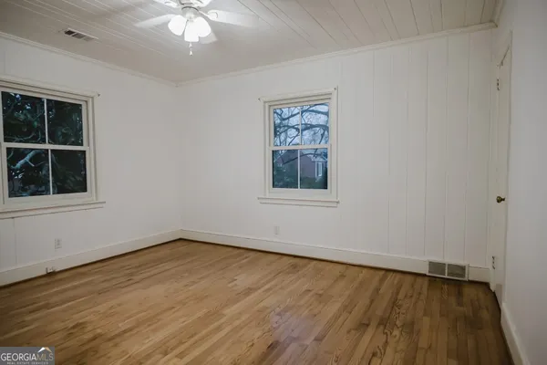an empty room with wooden floor and windows