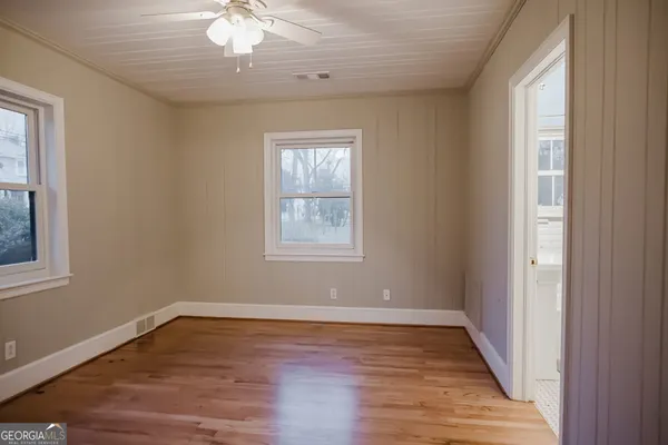 a view of empty room with wooden floor and fan