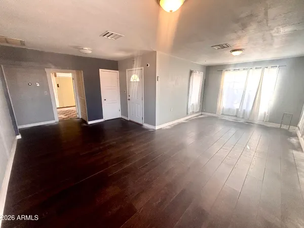 a view of an empty room with wooden floor and a window