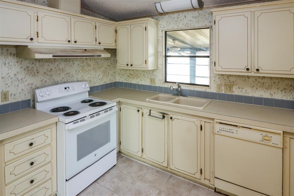 29200 South Jones Loop Road, Unit 176 Punta Gorda, FL 33950 - Photo 14 of 31 a kitchen with granite countertop white cabinets and white appliances