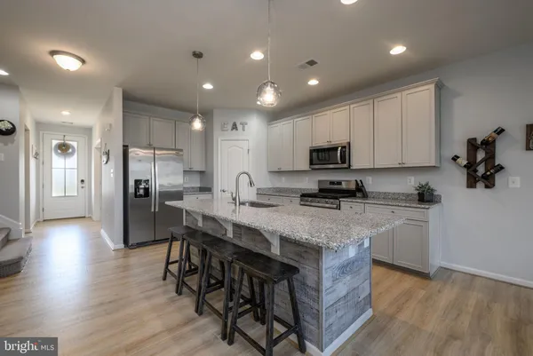 a kitchen with stainless steel appliances granite countertop a table chairs sink refrigerator and microwave