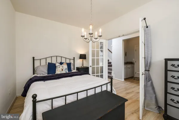 a bedroom with a bed a chandelier and a dresser