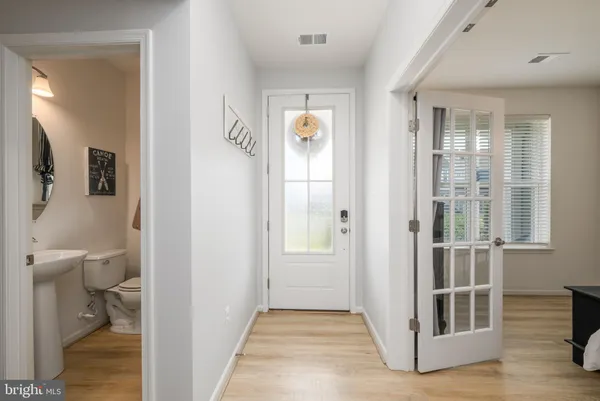 a view of a hallway with wooden floor and a bathroom