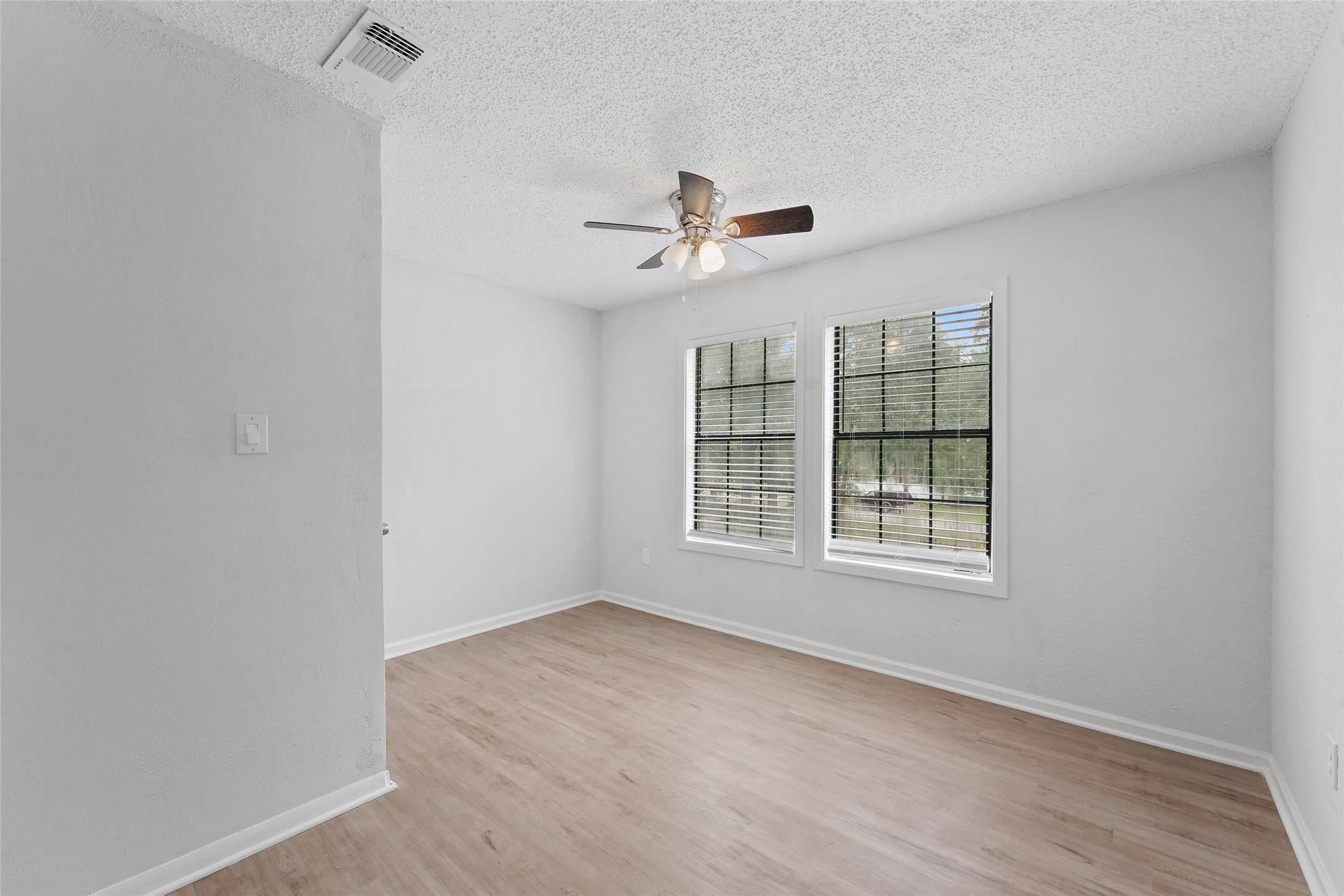18009 Split Oak Circle New Caney, TX 77357 - Photo 18 of 30 an empty room with wooden floor ceiling fan and windows