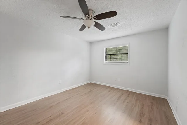 an empty room with wooden floor and ceiling fan