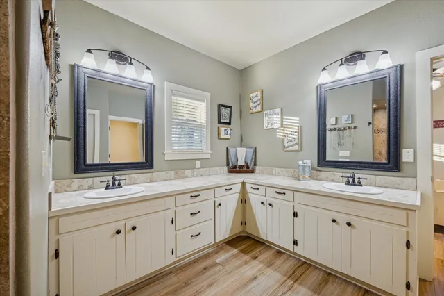 a bathroom with a double vanity sink and mirror with wooden floor