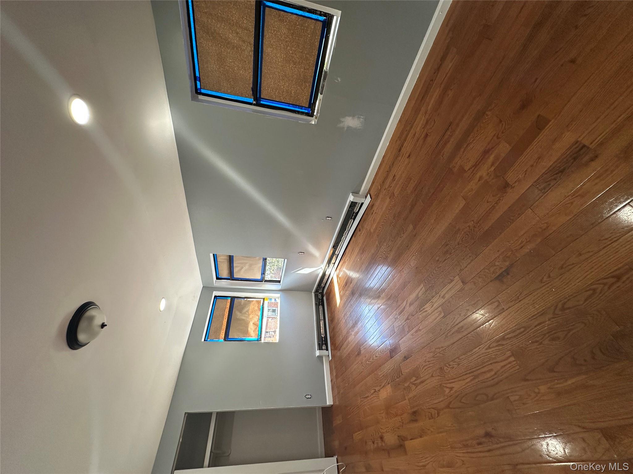 235-18 147th Road Queens, NY 11422 - Photo 2 of 5 an empty room with wooden floor and windows