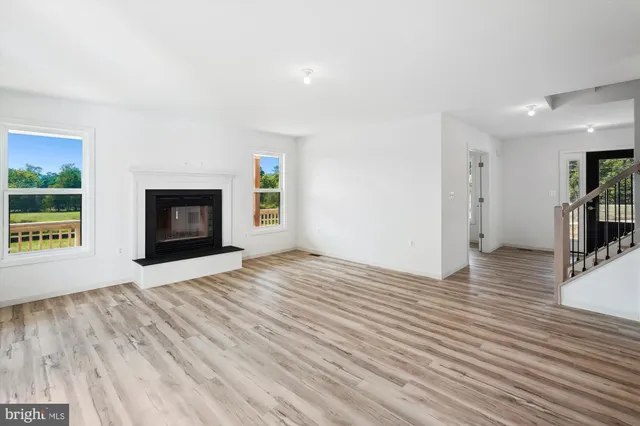 a view of empty room with wooden floor and fireplace