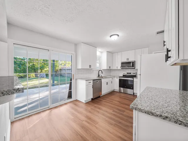 an empty room with wooden floor ceiling fan and window