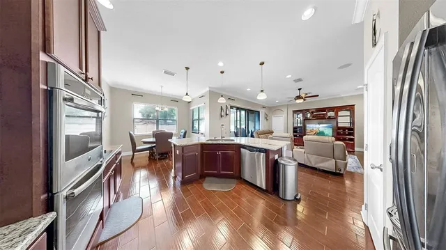 a kitchen with stainless steel appliances granite countertop a stove top oven a sink dishwasher a refrigerator and cabinets with wooden floor