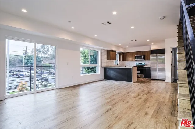a view of kitchen with stainless steel appliances kitchen island wooden floor and window