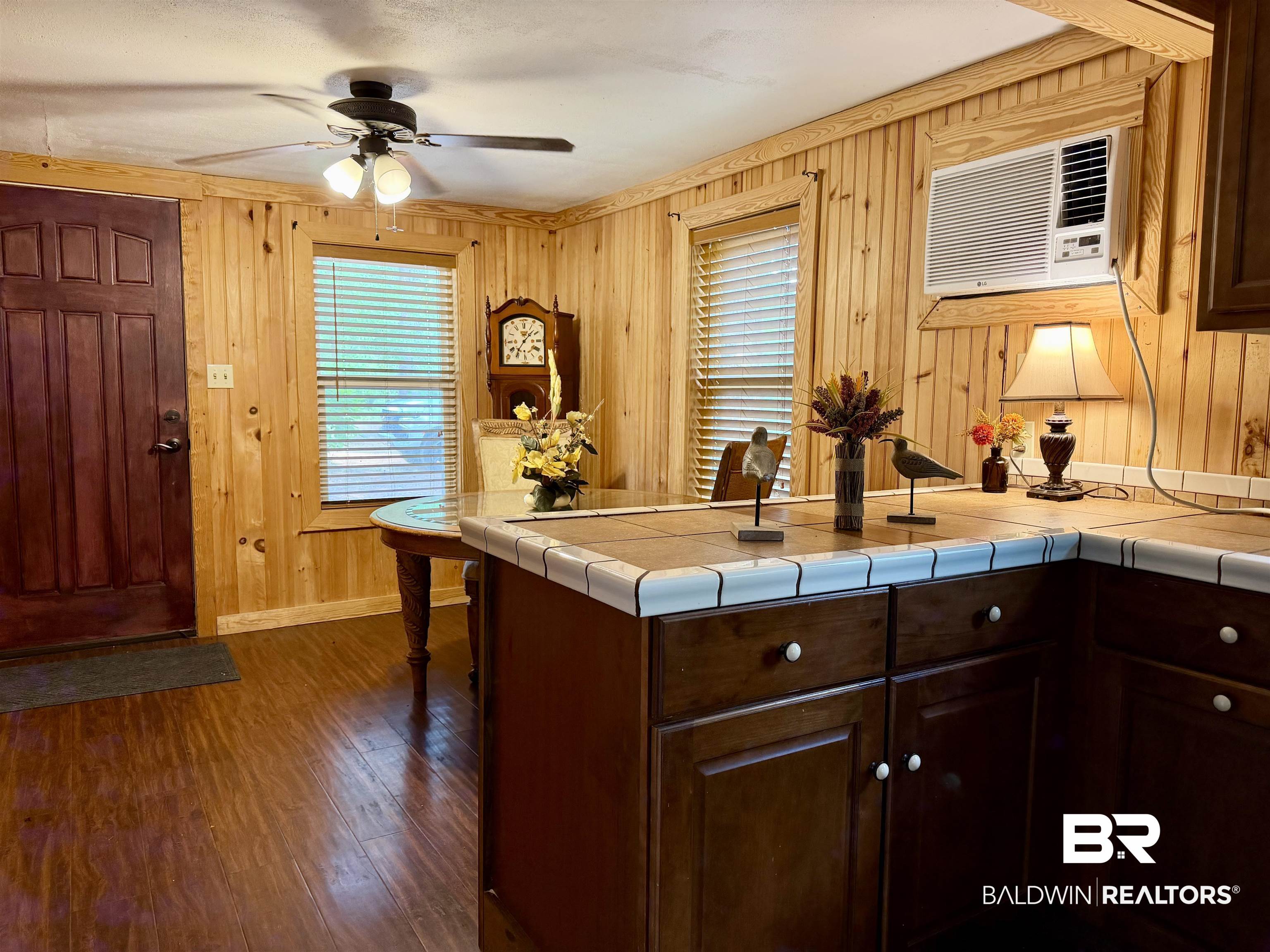 762 Buddy Lake Road Brewton, AL 36426 - Photo 8 of 20 Warm wood-paneled walls featuring multiple windows with blinds, rich wood-finish flooring, and a ceiling fan with integrated lighting