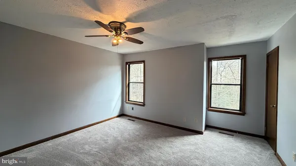 an empty room with windows and fan