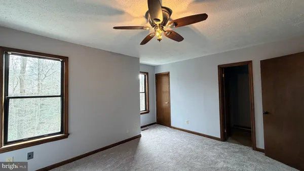 an empty room with windows and fan