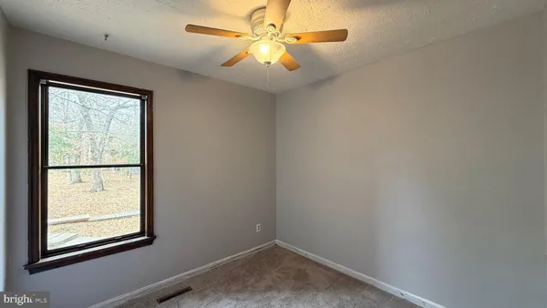 an empty room with windows and fan